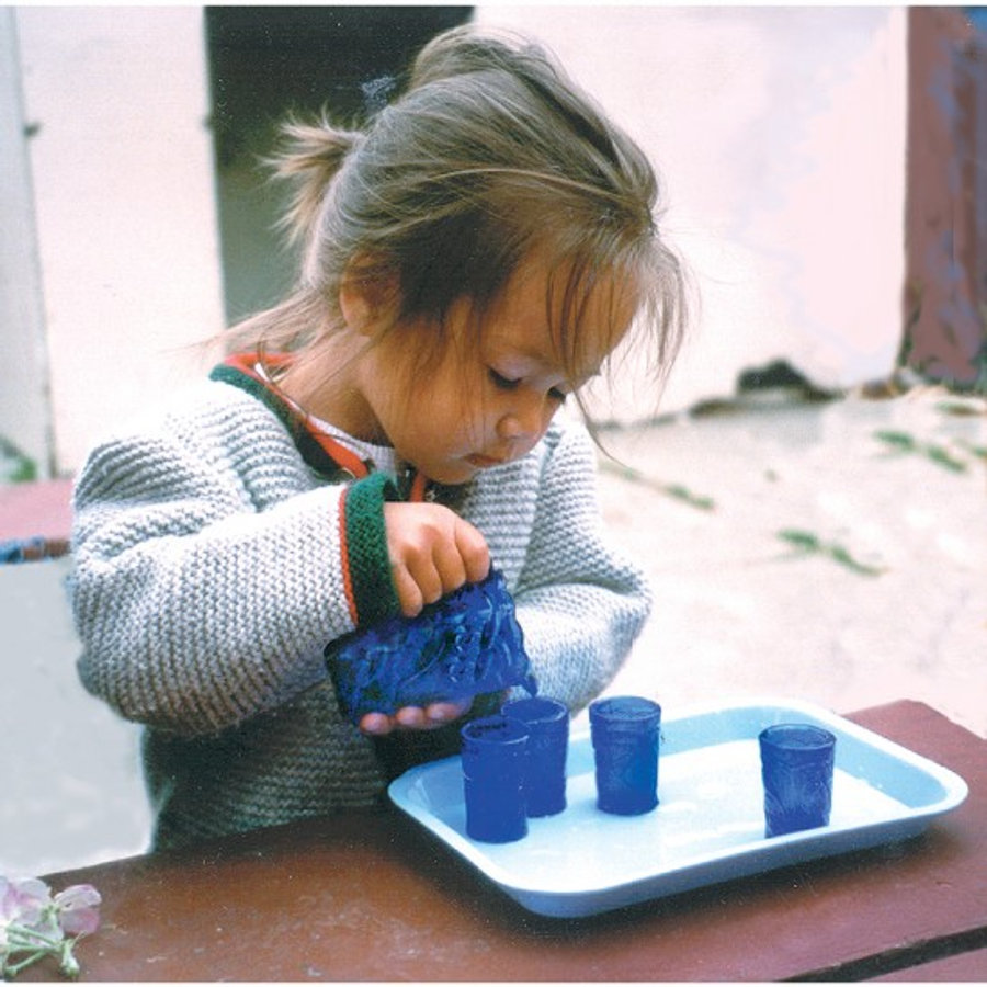 A young child carefully pouring water during a Montessori practical-life activity