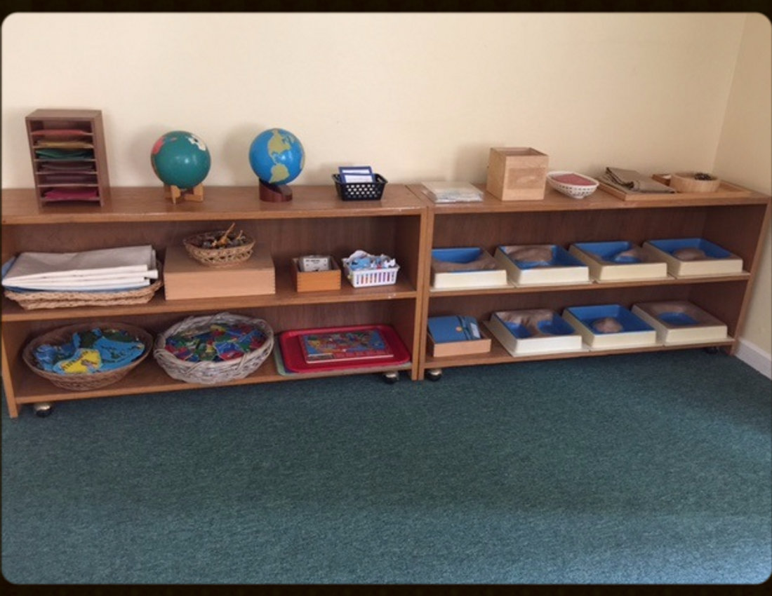 Montessori materials and globes arranged on low wooden shelves